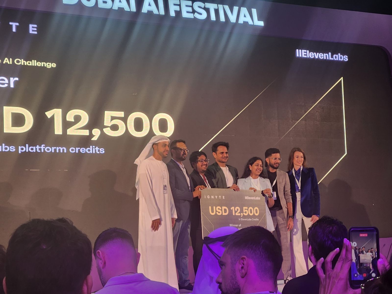 Winners on stage with the USD 12,500 prize board on screen